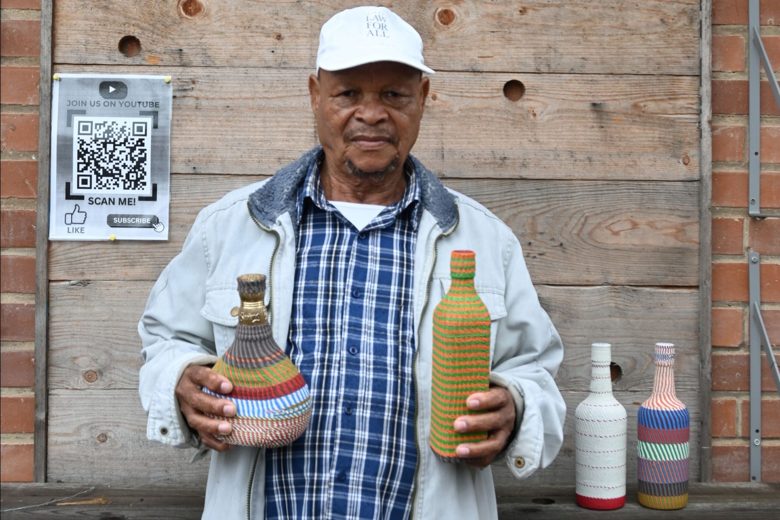 Zulu wire-weaver James Ndlela with his telephone wire covered bottles.